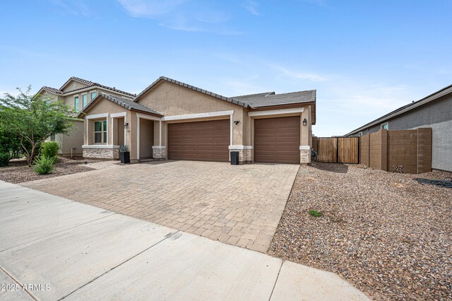 17968 W Hilton Ave, Goodyear, AZ 85338 - view of front of property with a garage, driveway, stucco siding, stone siding, and a gate