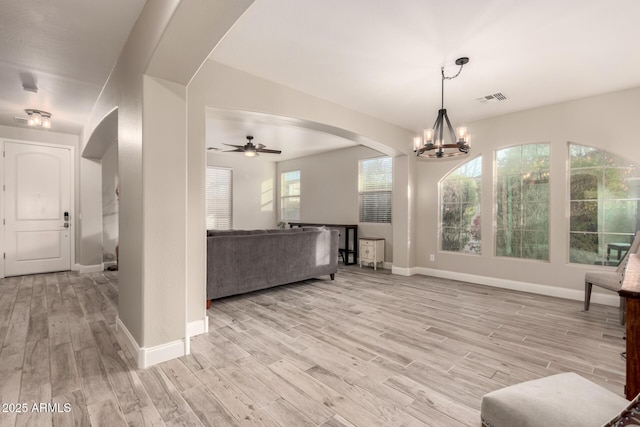 living room with ceiling fan with notable chandelier and light hardwood / wood-style flooring