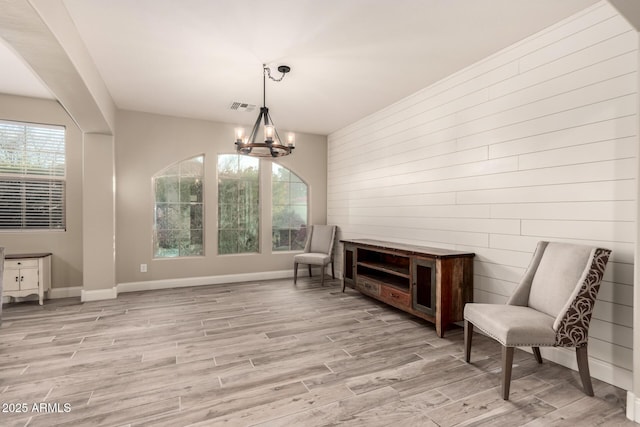 living area featuring light wood-type flooring, a notable chandelier, and plenty of natural light