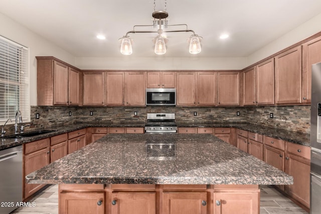 kitchen with hanging light fixtures, a center island, stainless steel appliances, and sink