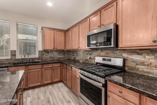 kitchen featuring tasteful backsplash, sink, dark stone counters, and appliances with stainless steel finishes