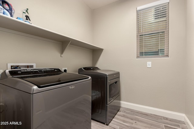 laundry area featuring washing machine and clothes dryer and light hardwood / wood-style flooring