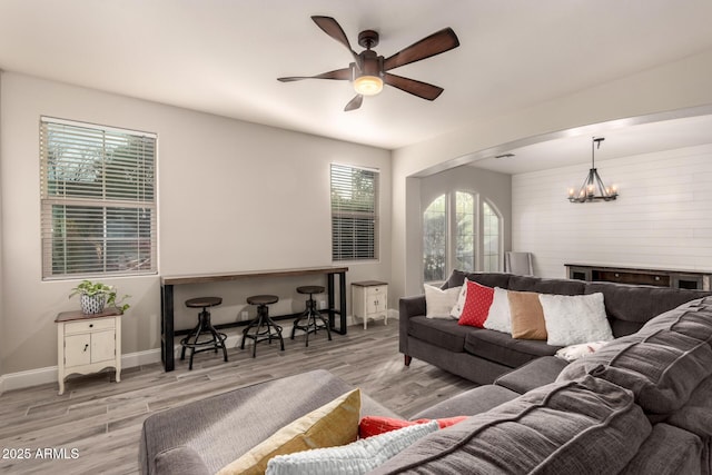 living room with ceiling fan with notable chandelier and light hardwood / wood-style flooring