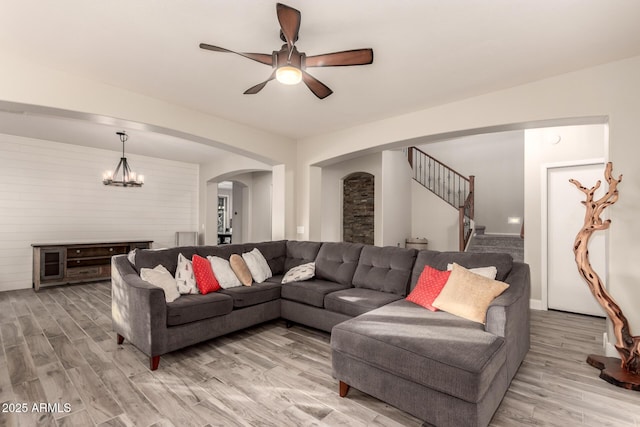 living room featuring ceiling fan with notable chandelier and hardwood / wood-style floors