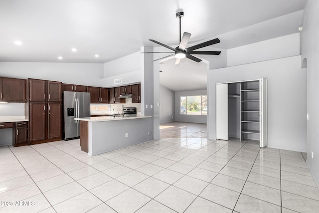 kitchen featuring appliances with stainless steel finishes, vaulted ceiling, light countertops, under cabinet range hood, and light tile patterned flooring