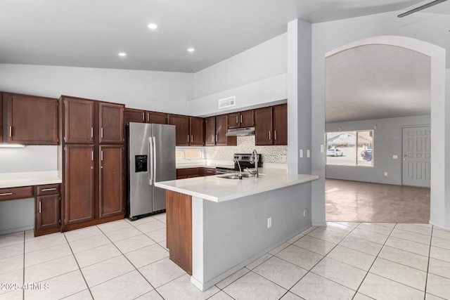 kitchen with light countertops, appliances with stainless steel finishes, vaulted ceiling, a sink, and under cabinet range hood