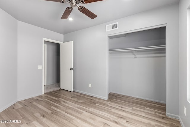 unfurnished bedroom with a closet, visible vents, baseboards, and wood finished floors