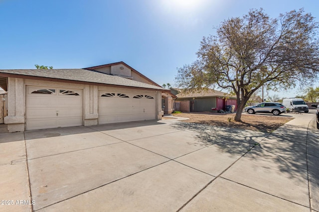 view of front of house with a garage, concrete driveway, and a shingled roof