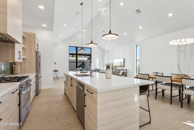 kitchen featuring pendant lighting, sink, appliances with stainless steel finishes, an island with sink, and light brown cabinetry