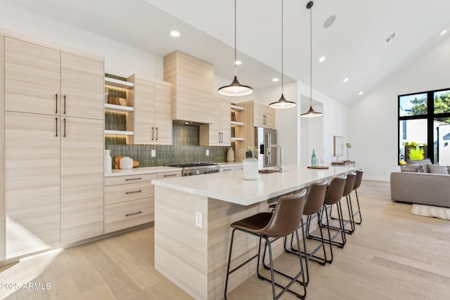 kitchen featuring high end refrigerator, light brown cabinets, and a kitchen island with sink