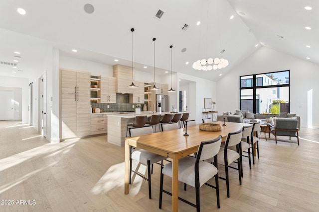 dining space with high vaulted ceiling and light wood-type flooring