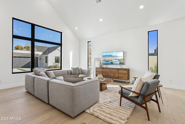 living room featuring high vaulted ceiling, light hardwood / wood-style floors, and a healthy amount of sunlight