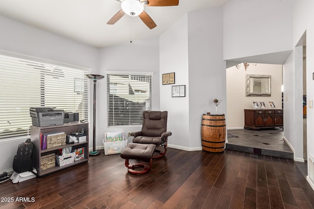 sitting room with dark wood-style floors, high vaulted ceiling, a ceiling fan, and baseboards