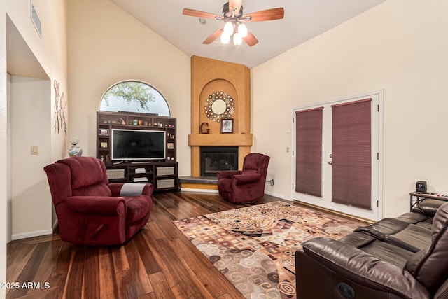 living area featuring high vaulted ceiling, a fireplace, visible vents, a ceiling fan, and dark wood finished floors