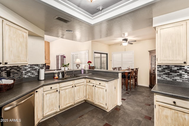 kitchen featuring visible vents, dishwasher, dark countertops, a peninsula, and a sink