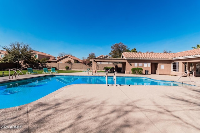 community pool with a patio area and fence