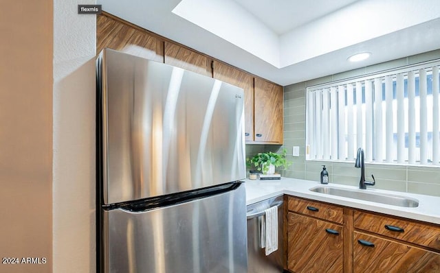 kitchen with appliances with stainless steel finishes, tasteful backsplash, and sink