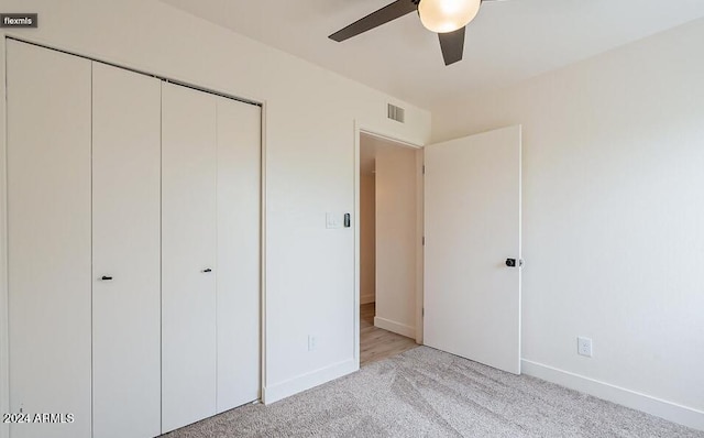 unfurnished bedroom featuring light carpet, a closet, and ceiling fan