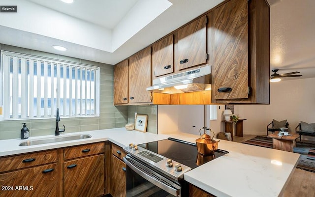 kitchen featuring tasteful backsplash, sink, electric range, kitchen peninsula, and hardwood / wood-style flooring