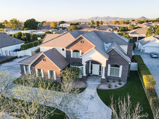 exterior space featuring a residential view, fence, a mountain view, and a tiled roof