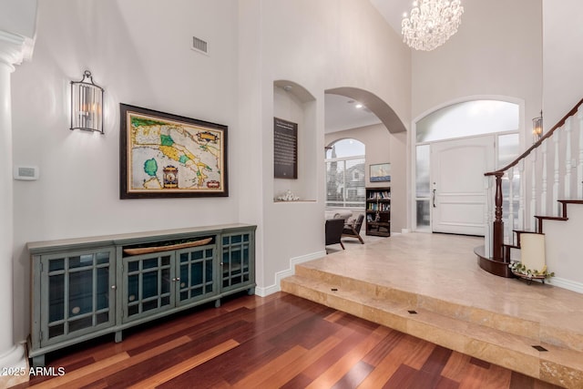 entrance foyer with a notable chandelier, stairway, a high ceiling, wood finished floors, and baseboards