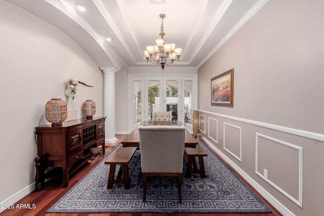 dining space with french doors, dark wood finished floors, decorative columns, a decorative wall, and an inviting chandelier