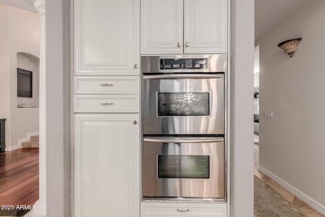 kitchen with baseboards, white cabinets, and stainless steel double oven