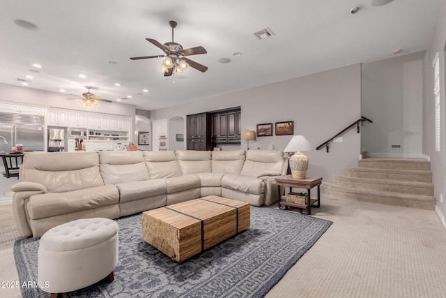 carpeted living area with a ceiling fan, recessed lighting, visible vents, and stairway