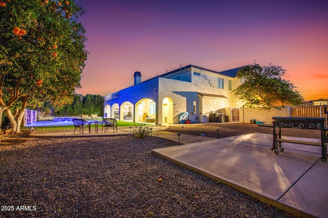 rear view of property with central AC unit, fence, stucco siding, an outdoor pool, and a patio area