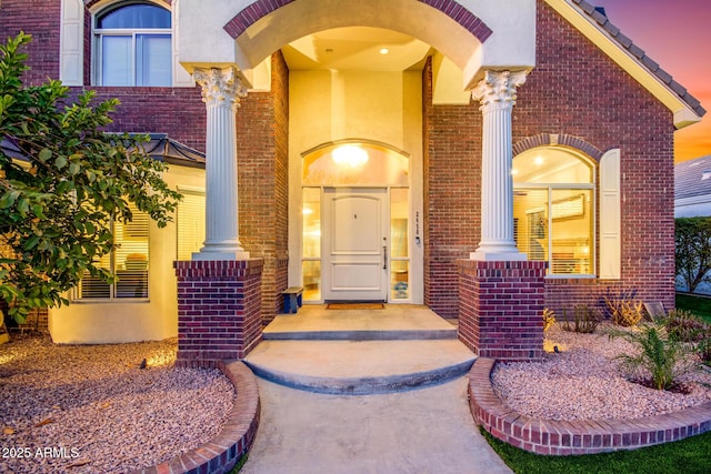 doorway to property with brick siding and stucco siding