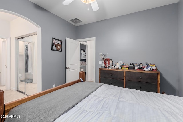 bedroom featuring visible vents, arched walkways, a ceiling fan, tile patterned floors, and a closet