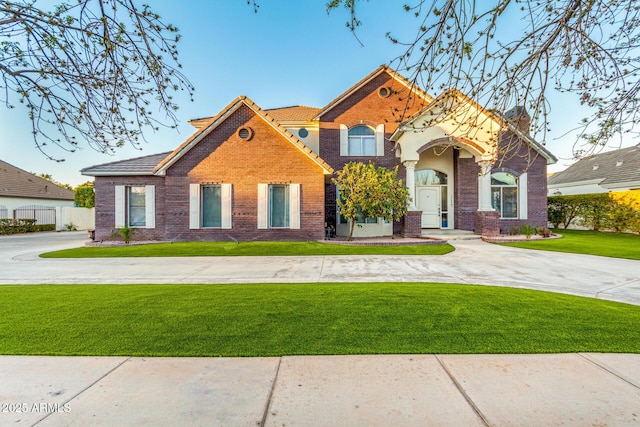 view of front of home featuring fence, a front lawn, and brick siding