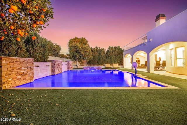 pool at dusk featuring a patio, a lawn, a fenced backyard, and an outdoor pool