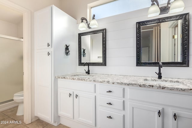 bathroom featuring tile patterned flooring, vanity, an enclosed shower, and toilet