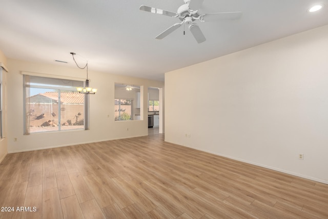 unfurnished living room featuring light hardwood / wood-style flooring and ceiling fan with notable chandelier