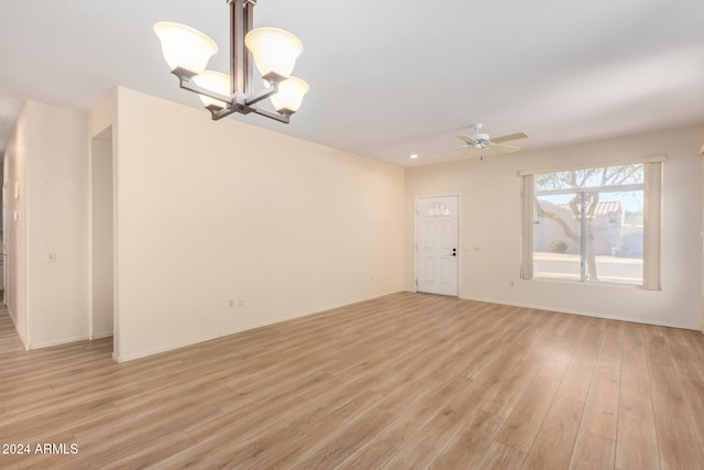 empty room with ceiling fan with notable chandelier and light wood-type flooring