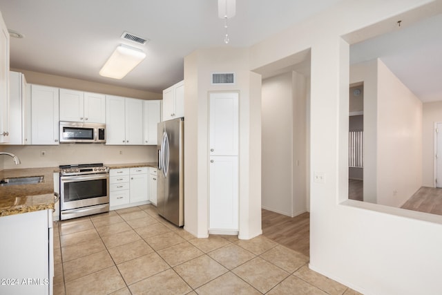 kitchen featuring white cabinetry, light wood-type flooring, light stone counters, and appliances with stainless steel finishes