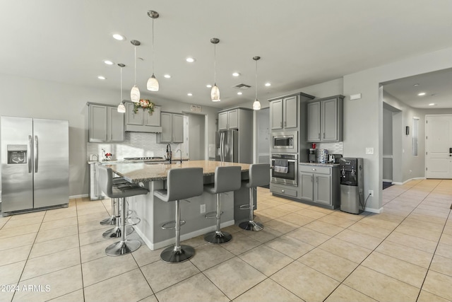 kitchen with stainless steel appliances, tasteful backsplash, a kitchen breakfast bar, pendant lighting, and light tile patterned floors