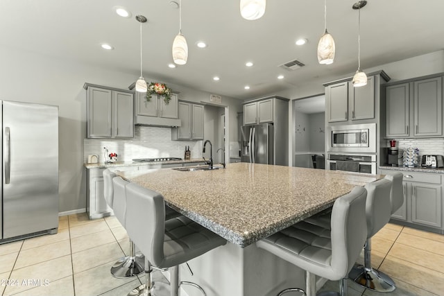 kitchen with light stone countertops, hanging light fixtures, and appliances with stainless steel finishes