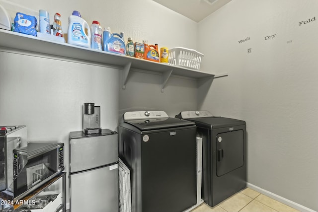 clothes washing area featuring light tile patterned flooring and washer and dryer