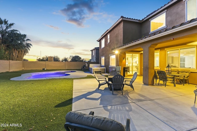 patio terrace at dusk with a fenced in pool and a yard