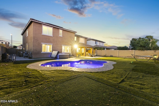 exterior space featuring a swimming pool with hot tub, a yard, and a patio