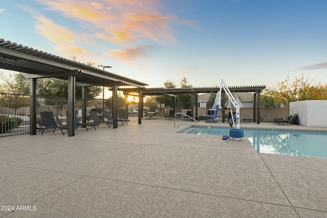 pool at dusk featuring a pergola and a patio