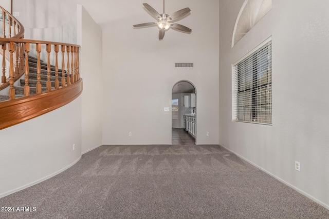 unfurnished room featuring ceiling fan, a high ceiling, and dark colored carpet