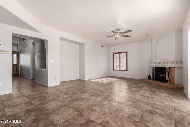 unfurnished living room featuring ceiling fan and a tiled fireplace