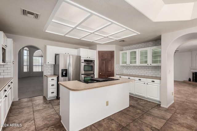 kitchen with tasteful backsplash, white cabinetry, a kitchen island, and stainless steel appliances