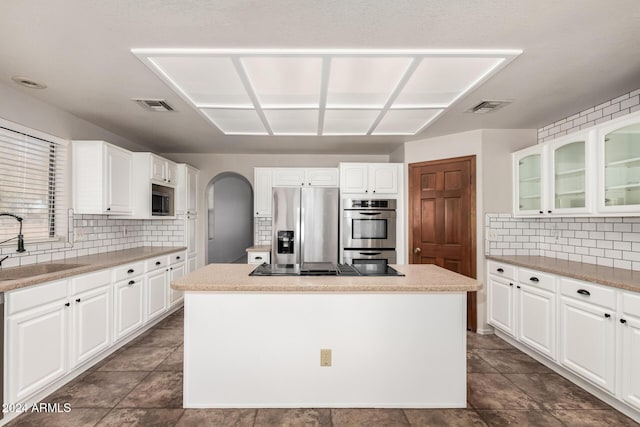 kitchen with white cabinets, a center island, stainless steel appliances, and sink