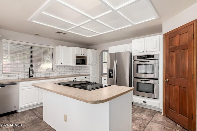 kitchen featuring white cabinets, a center island, appliances with stainless steel finishes, and sink