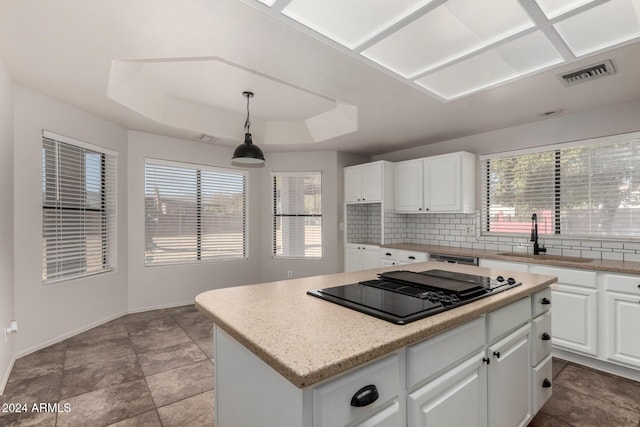 kitchen with a center island, white cabinetry, hanging light fixtures, and sink