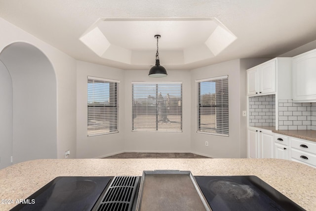 kitchen with pendant lighting, backsplash, a raised ceiling, and white cabinets